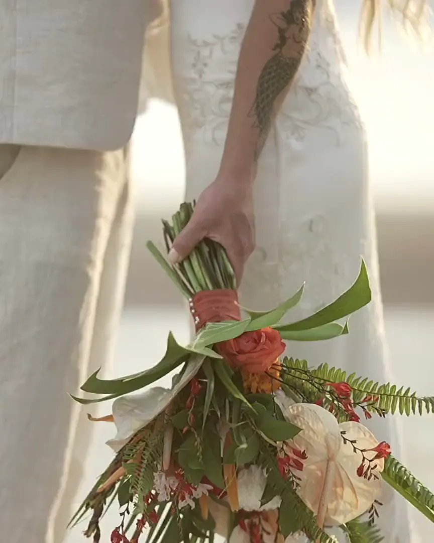 Novios en la playa, ella con su ramo de flores